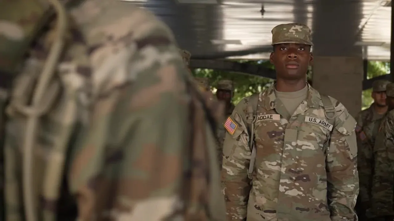 U.S. Army soldier in uniform standing in formation with other soldiers in the background