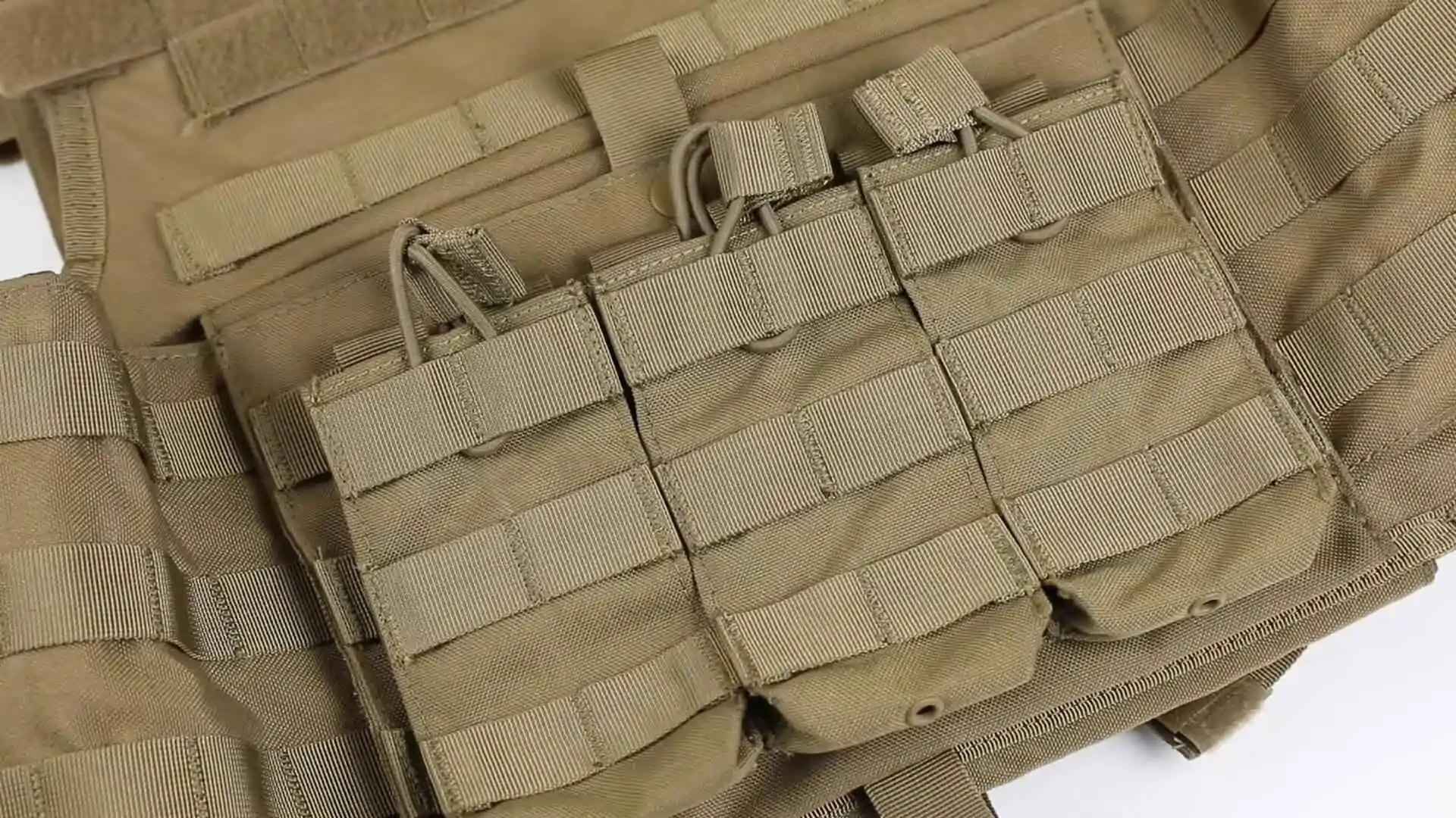 Close-up of a tan MOLLE tactical vest laid flat, showing three empty magazine pouches and horizontal webbing