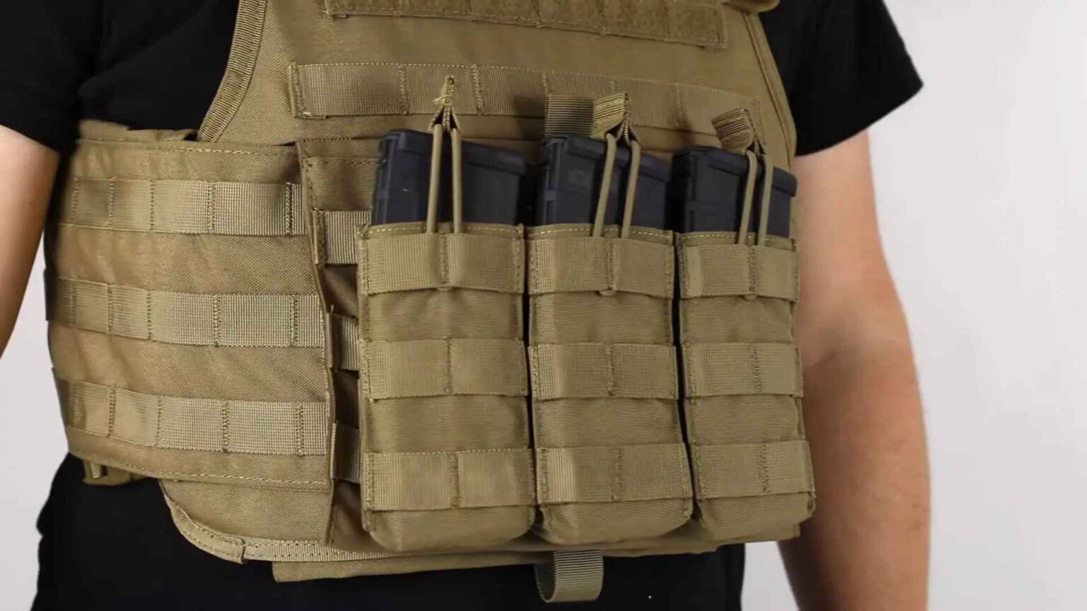 Close-up of a tan MOLLE tactical vest with four rifle magazine pouches attached and filled
