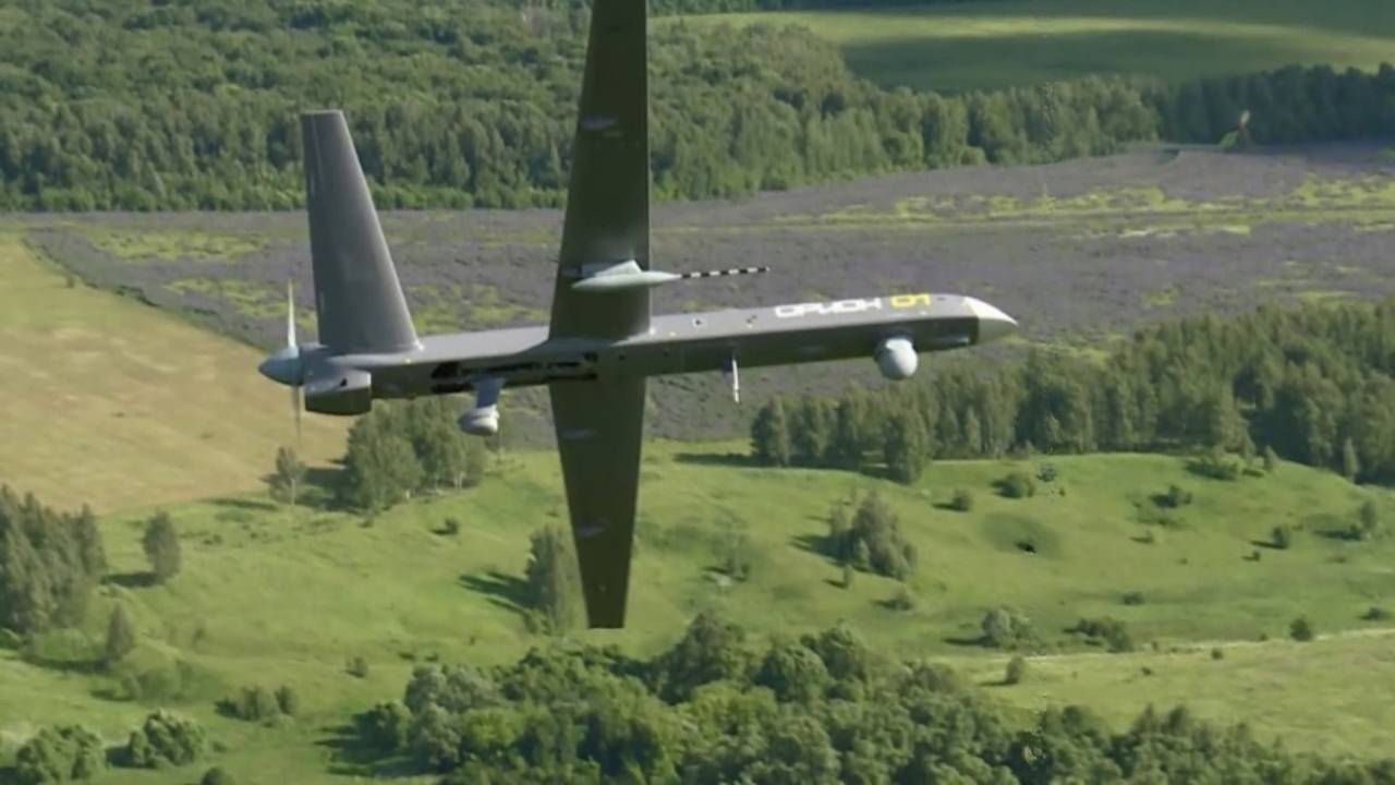 Kronshtadt Orion UAV in mid-flight above forested terrain, equipped with surveillance systems and sensors for ISR missions
