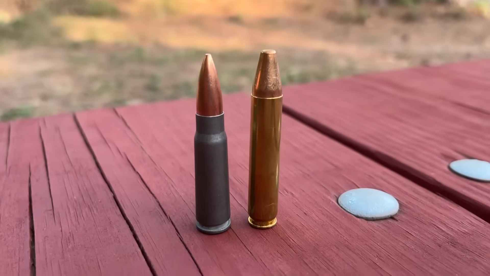 Side-by-side comparison of .350 Legend and .308 Winchester cartridges on a red wooden surface