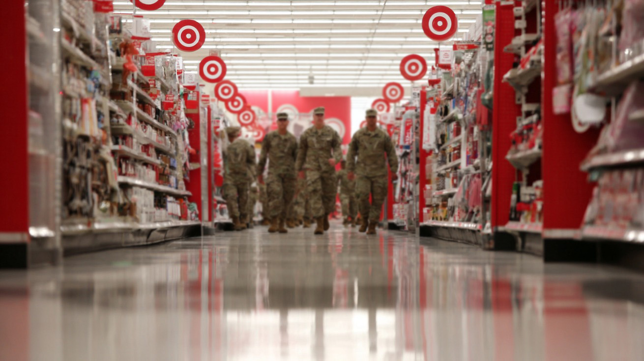 Group of uniformed military personnel walking down an aisle in a brightly lit Target store